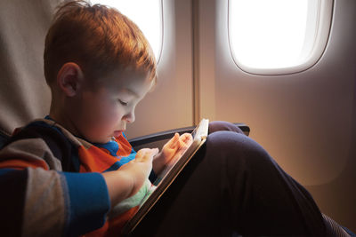 Close-up of boy using digital tablet in airplane