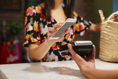 Close-up of customer paying cashless with smartphone at counter of a store