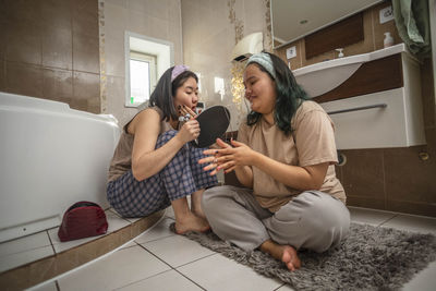 Asian laughing beauties begin their morning routine with acne treatment and face massage in bathroom