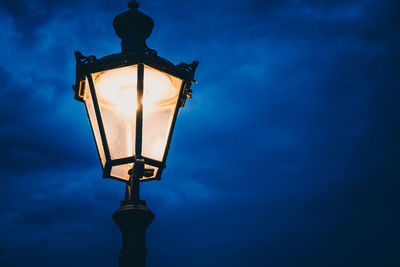 Low angle view of illuminated street light against blue sky