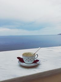 Close-up of coffee on table by sea against sky