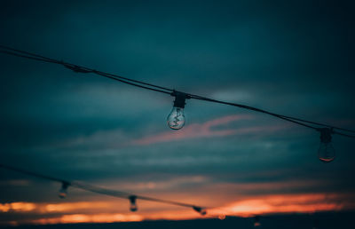 Low angle view of electricity pylon against sky during sunset