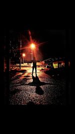 Silhouette man walking on illuminated street at night