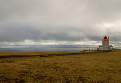 Lighthouse by sea against sky