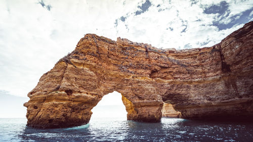 Rock formation in sea against sky