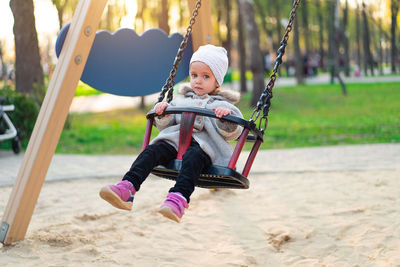 Full length portrait of girl sitting on swing at park