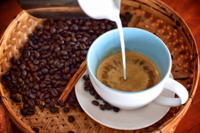 High angle view of milk pouring in coffee cup on table