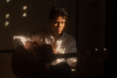 Young man sitting in the dark