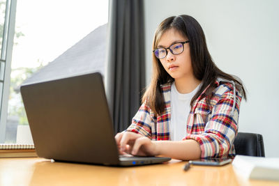 Mid adult woman using mobile phone while sitting on table