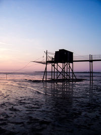 Silhouette lifeguard hut on beach against sky during sunset