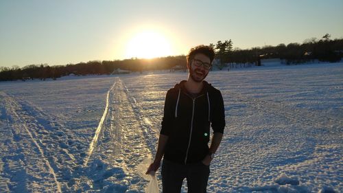 Portrait of smiling young woman standing on snow field