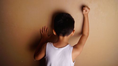 Rear view of boy standing in front of wall at home