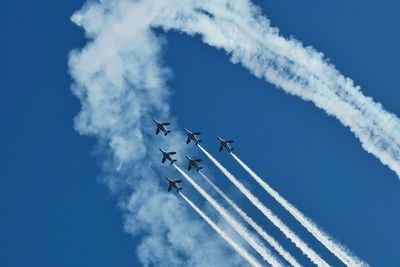 Low angle view of helicopter against blue sky