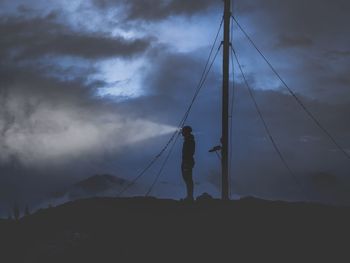 Low angle view of silhouette person holding rope against sky