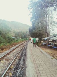 Rear view of man walking on railroad track