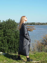 Side view of woman standing by plants against sky