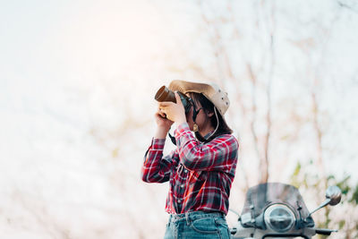 Side view of young woman standing against trees