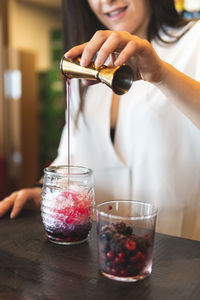 Midsection of man pouring drink in glass on table