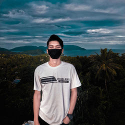 Young man wearing sunglasses standing against sky