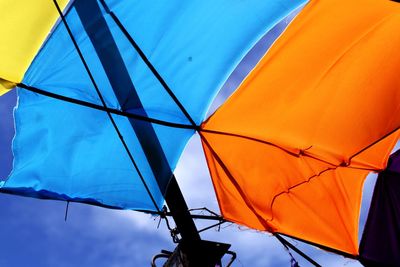 Low angle view of multi colored umbrella against blue sky