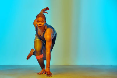 Portrait of woman exercising in front of wall