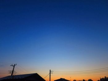 Low angle view of silhouette electricity pylon against clear sky