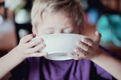 Close-up of boy drinking milk from bowl