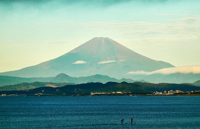 Scenic view of sea and volcanic mountain against cloudy sky in the morning