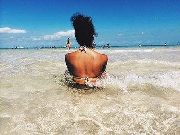 Rear view of young woman in sea against sky