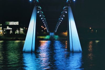 Illuminated bridge over river at night