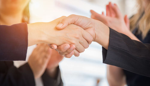 Close-up of businesswomen shaking hands with colleagues