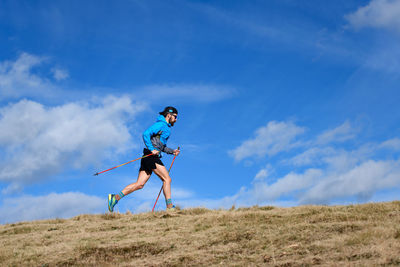 Rear view of man walking on field against sky