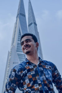 Low angle portrait of young man standing against sky