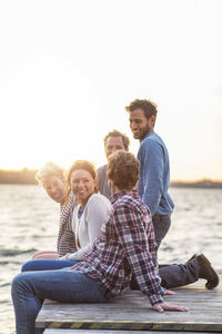 Happy friends on pier against clear sky