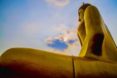 Low angle view of giant buddha statue against sky