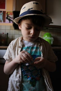 Cute boy wearing hat holding bag indoors