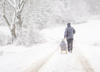 Rear view of man walking on snow