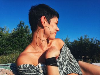 Low angle view of young woman looking away against clear sky