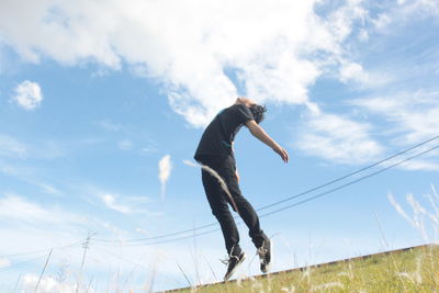 Low angle view of man standing on grass against sky