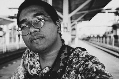 Portrait of man wearing eyeglasses at railroad station