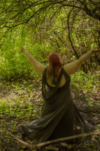 Rear view of woman standing against trees