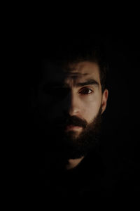 Close-up portrait of young man against black background