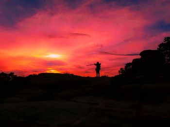 Silhouette man against orange sky