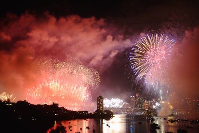 Firework display over river against sky