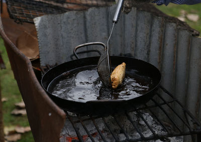 Person holding meat on barbecue grill