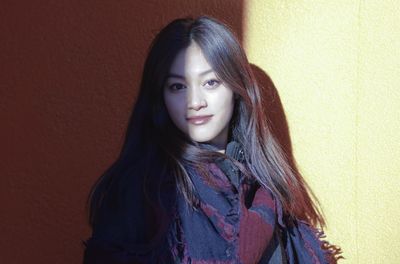 Portrait of smiling young woman standing against wall