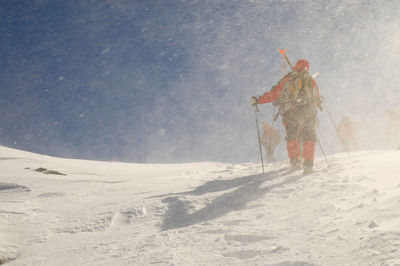 Person skiing on snow covered mountain against sky