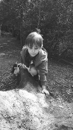 High angle view of boy climbing on rock in forest