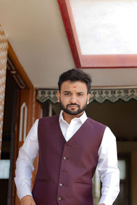 Portrait of businessman standing against wall