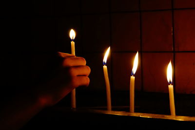 Cropped hand holding illuminated candle